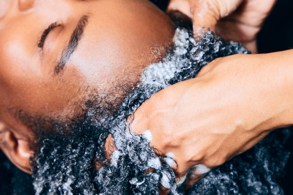 stylist with hands in curly hair -  washing curly hair at the sink