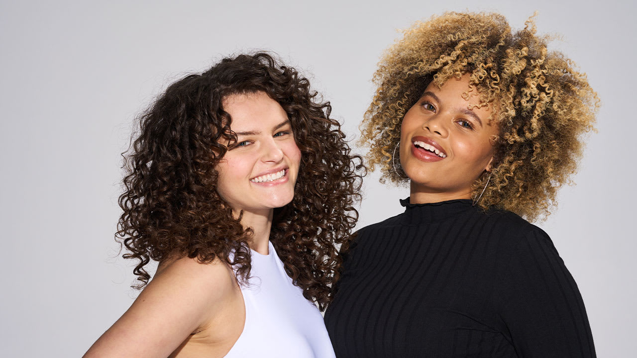 two curly hair models smiling side by side