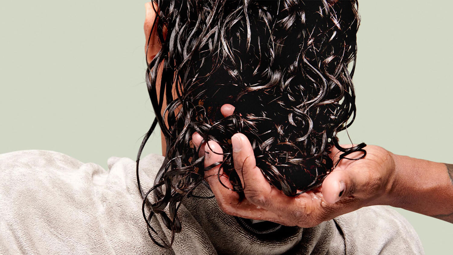 hair stylist washes woman's curly hair at a sink