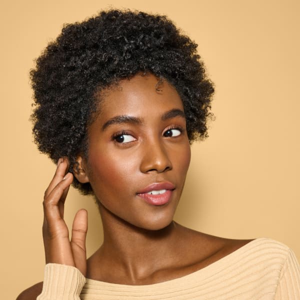 woman with coily hair touching hair