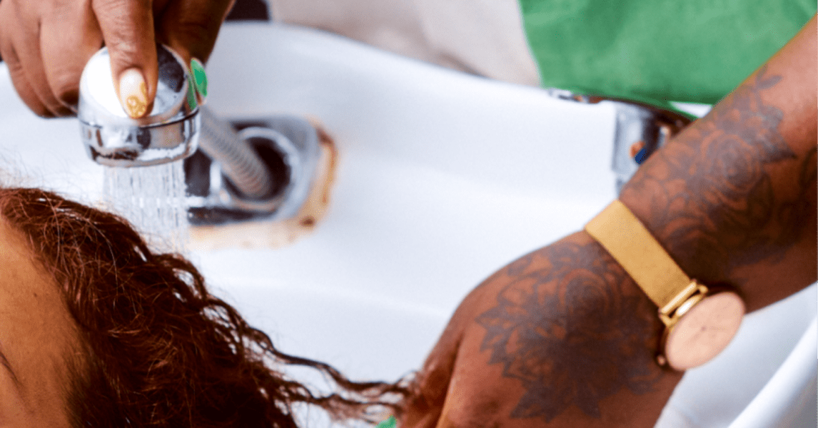 woman with curly hair at the sink, hands in hair