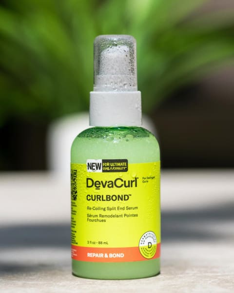 DevaCurl CurlBond™ in a green spray bottle with a cap, covered in condensation