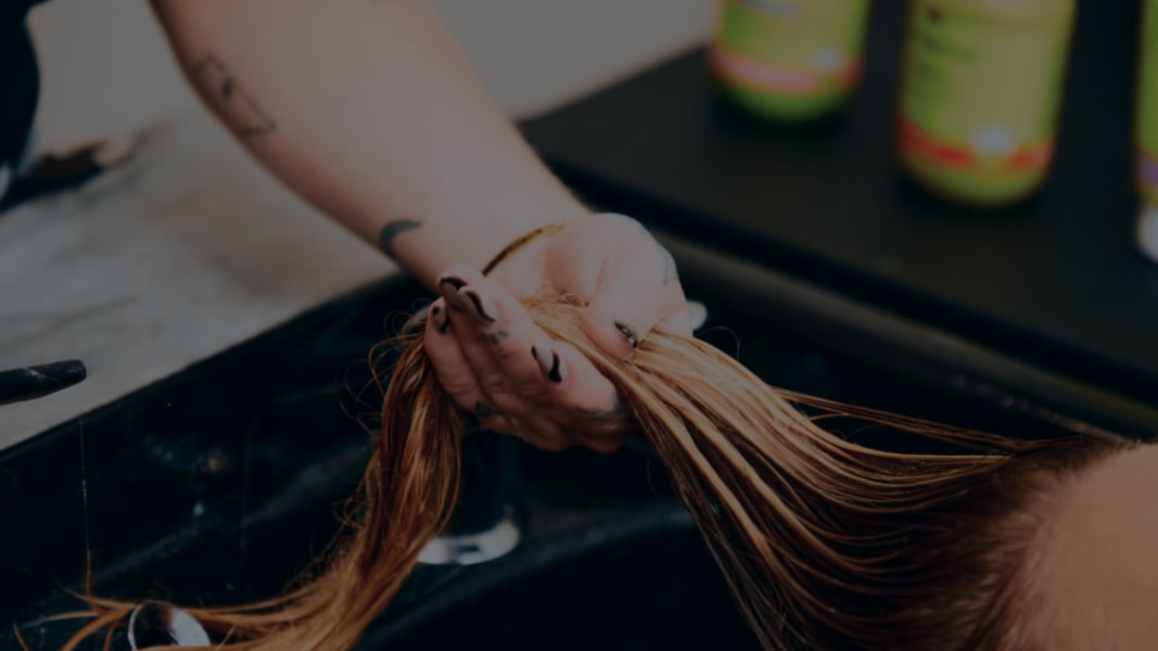 finger raking wavy hair at the sink