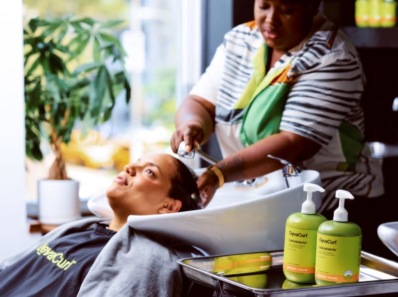 stylist with hands in hair at the sink and CurlHeights bottles