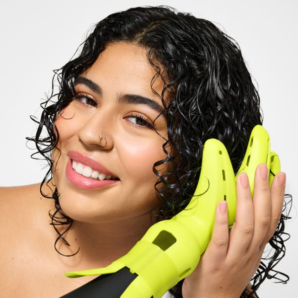 woman with dark curly hair smiling and using the DevaFuser