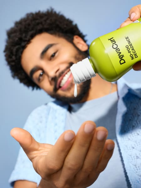 Man with curly, coarse hair squeezing No-Poo Decadence in hand