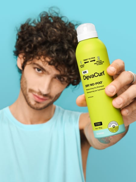 man with curly hair holding Dry No-Poo can