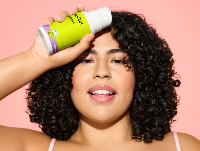 woman with curly hair holding SuperCream bottle