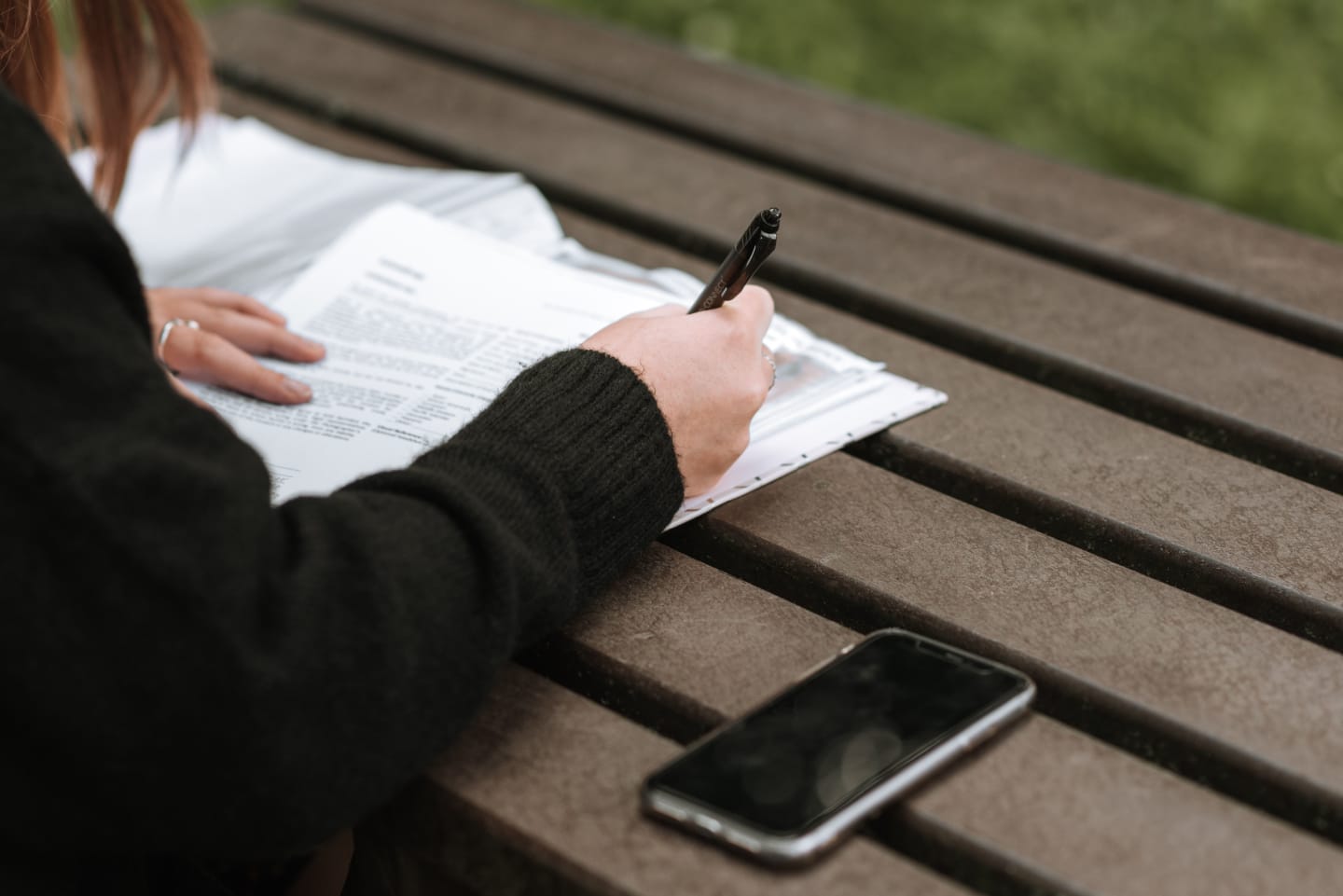 A person writing notes on a printed PRD.