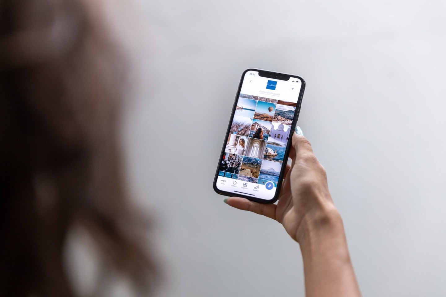 An individual holds a smartphone displaying a series of images within an application.