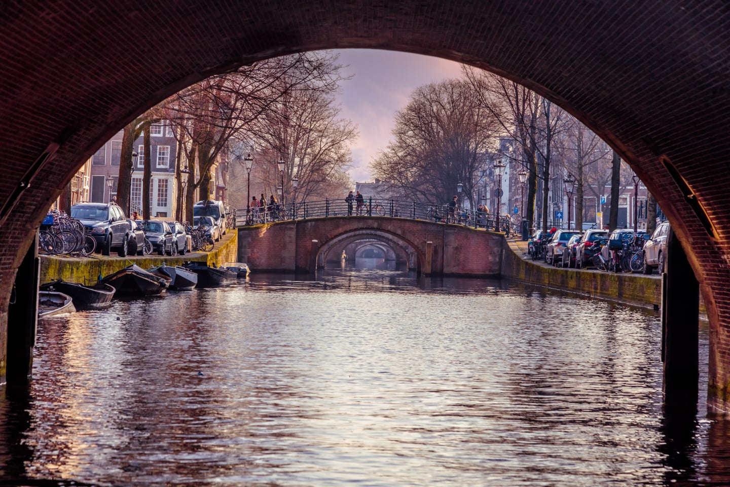 A picture of a canal taken beneath a bridge in Amsterdam.