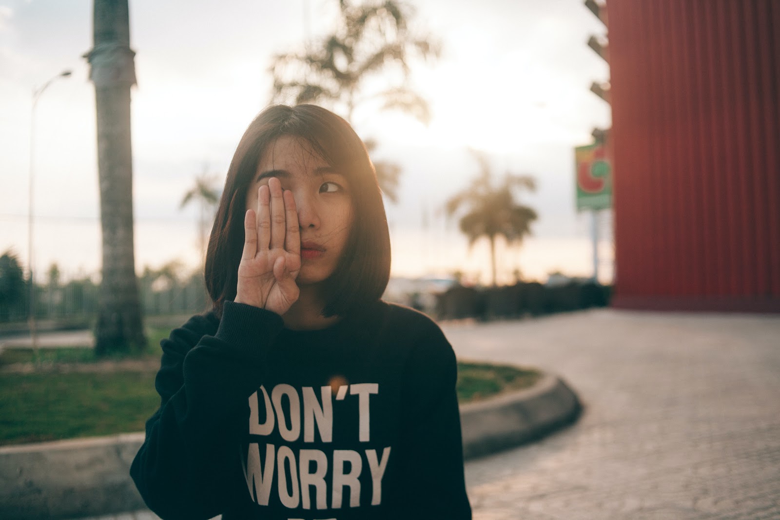 A young woman wearing a black sweatshirt with words on it reading, "Don't worry" in bold white capital letters.