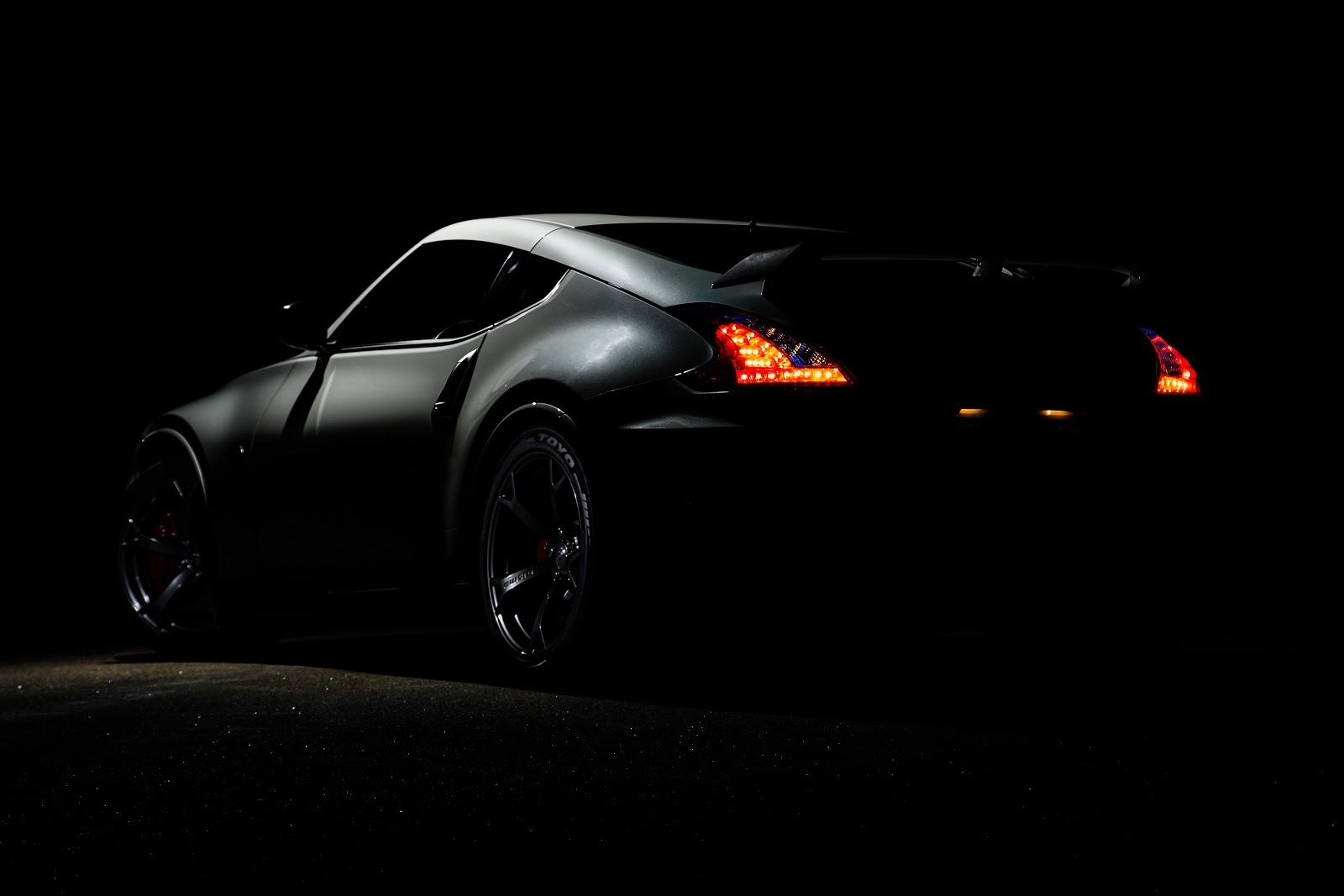 An image of a car in a very dark space. The make or model is hard to determine, but it appears to be sporty and sleek.