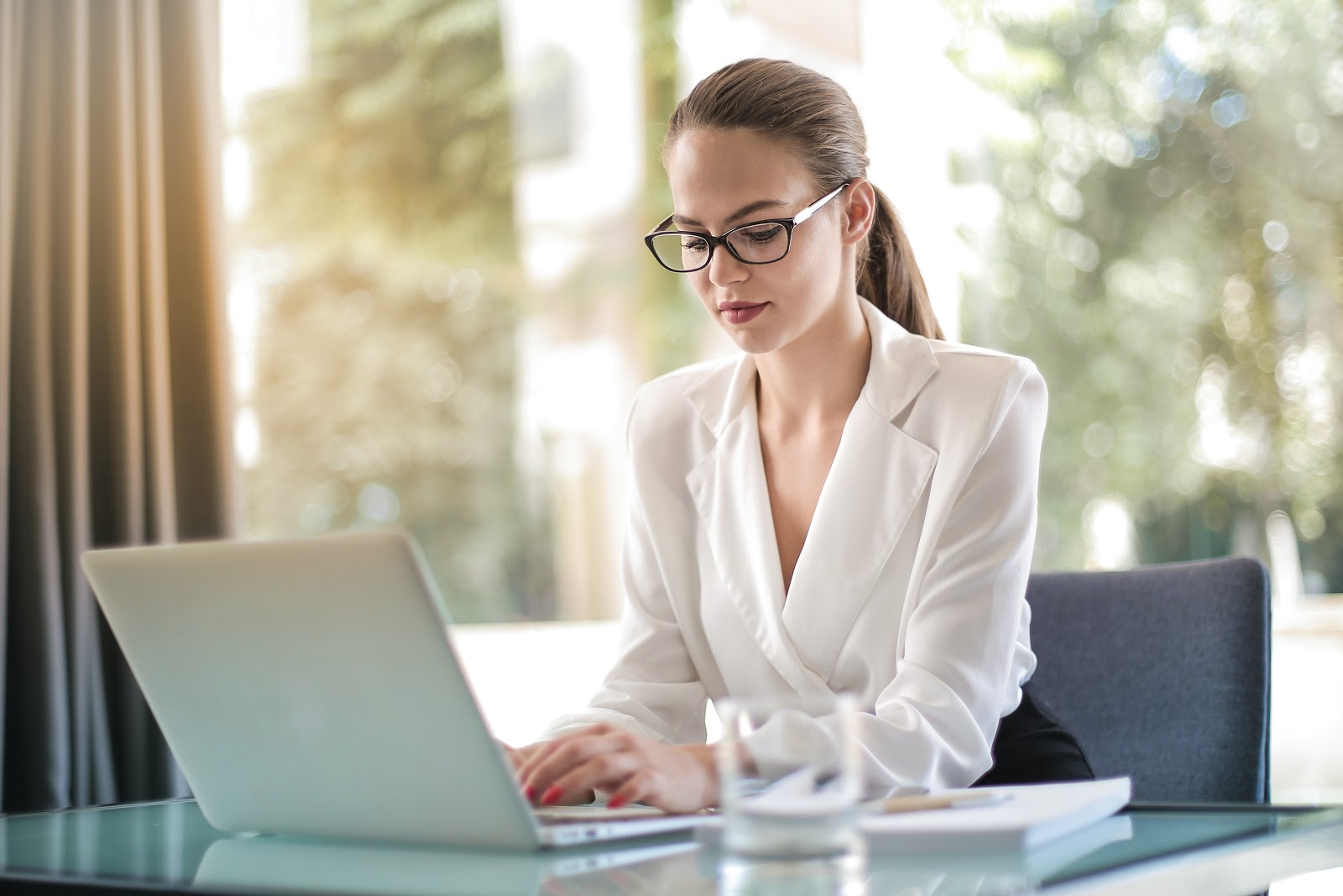 A professionally dressed woman works at her laptop.