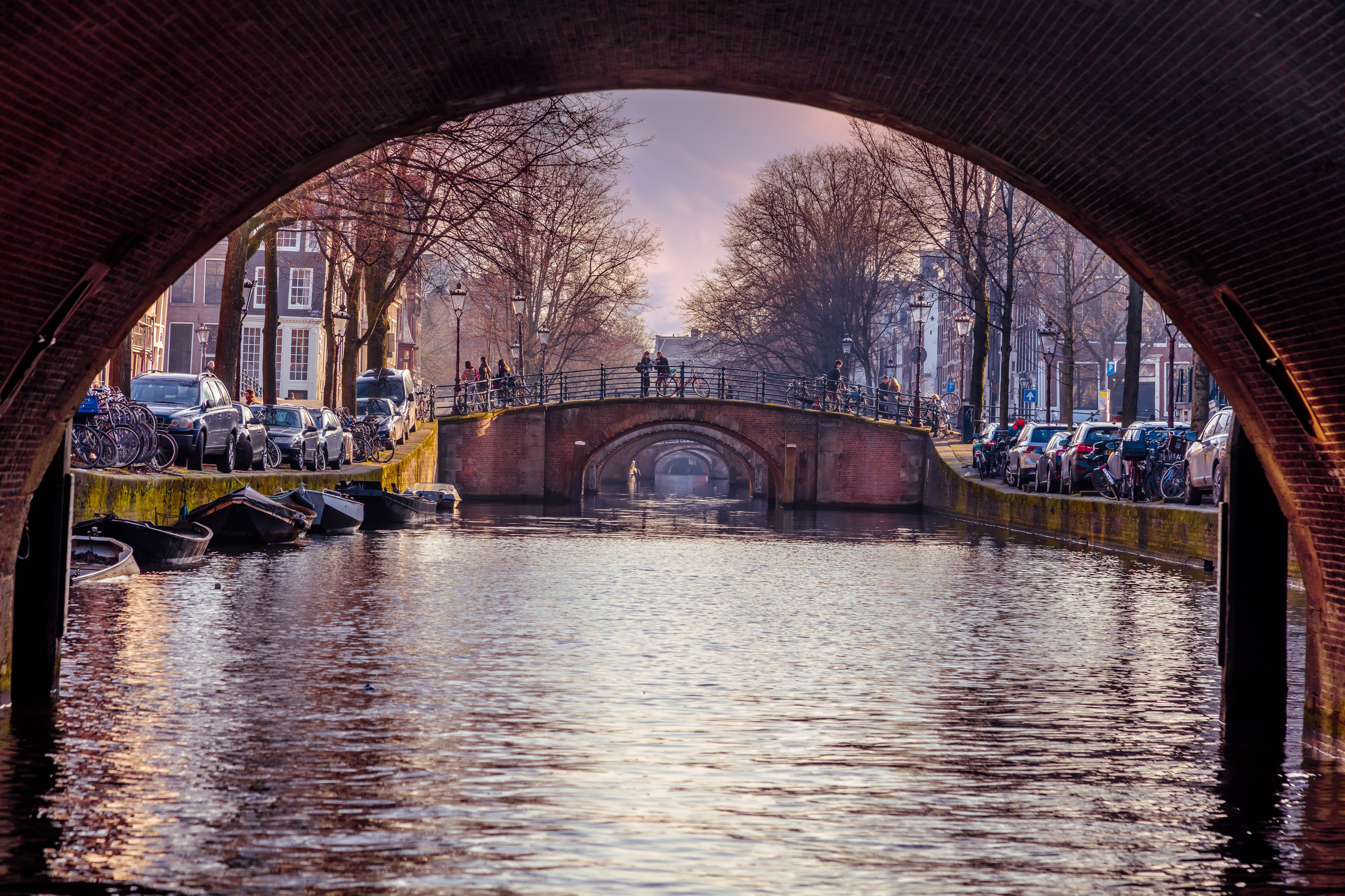 A picture of a canal taken beneath a bridge in Amsterdam.
