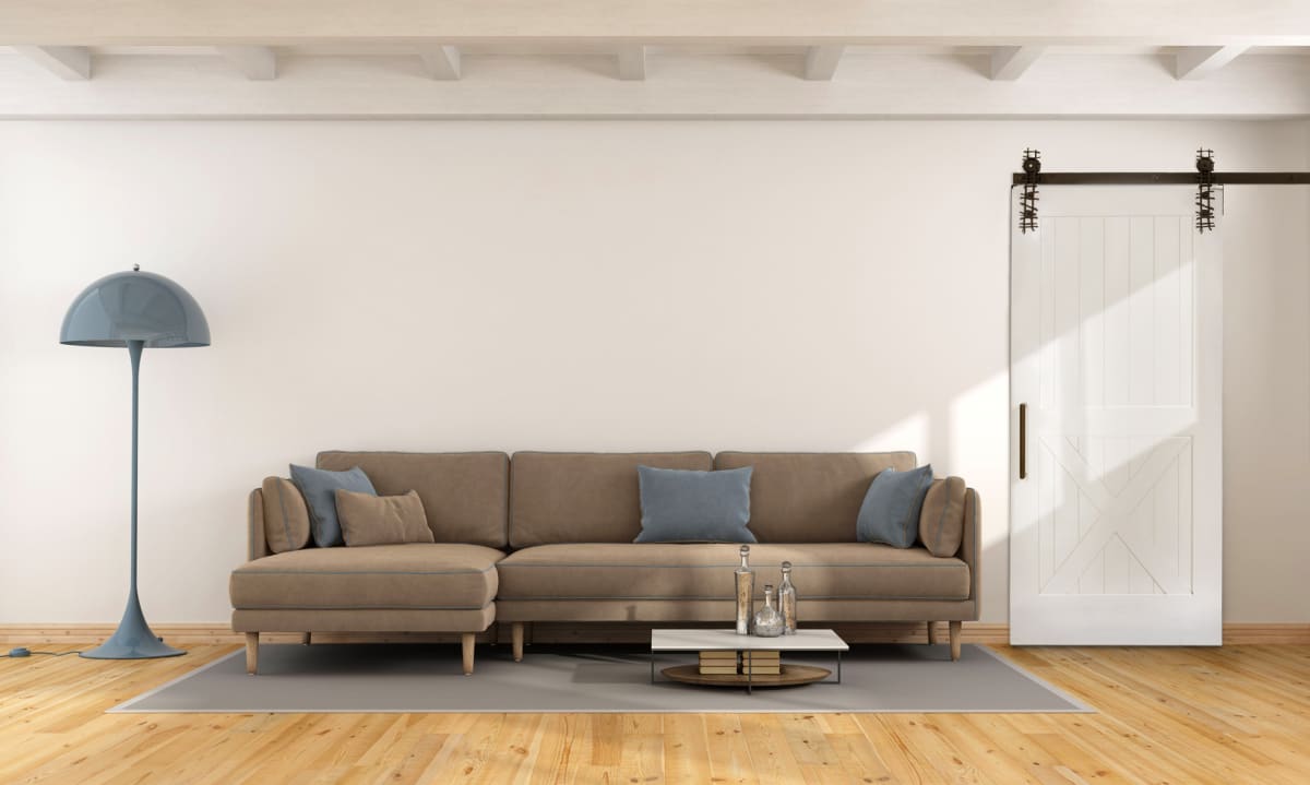 A white Half X barn door on a dark track beside a sofa and floor lamp.