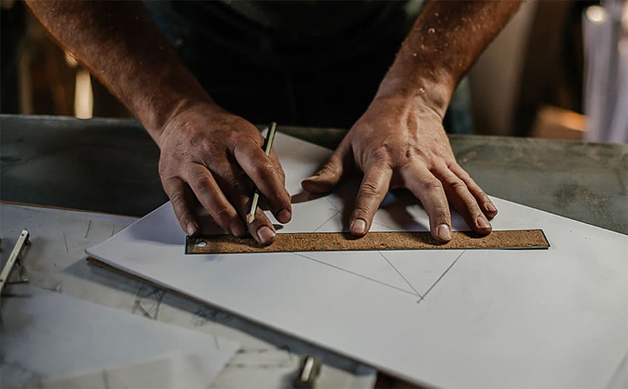 Rustica craftsperson carefully measuring and drawing a custom design by hand