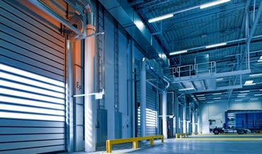 inside of an industrial building showing two garage style doors 42trreeqq