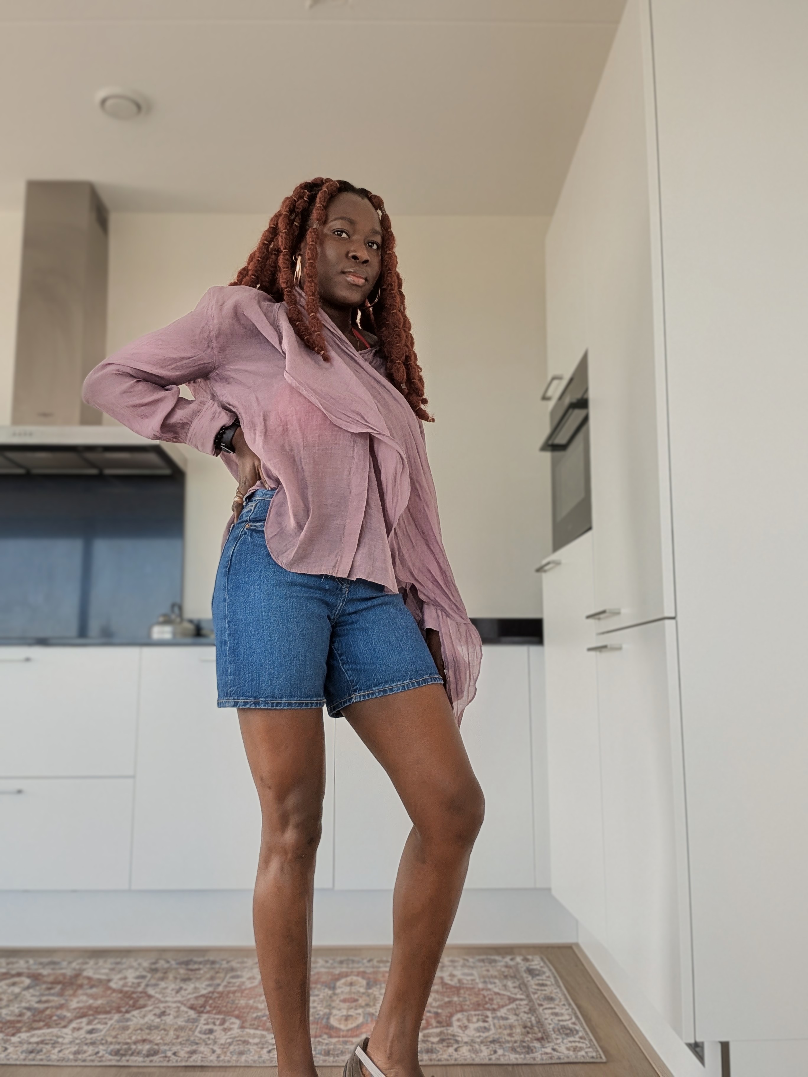 Picture of Olu wearing a pink shirt, blue jean shorts, beach ready
