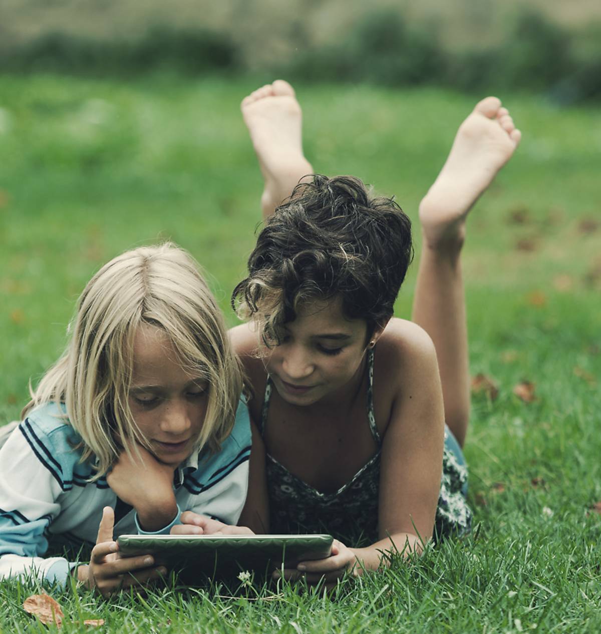 Kinder mit Tablet auf Wiese