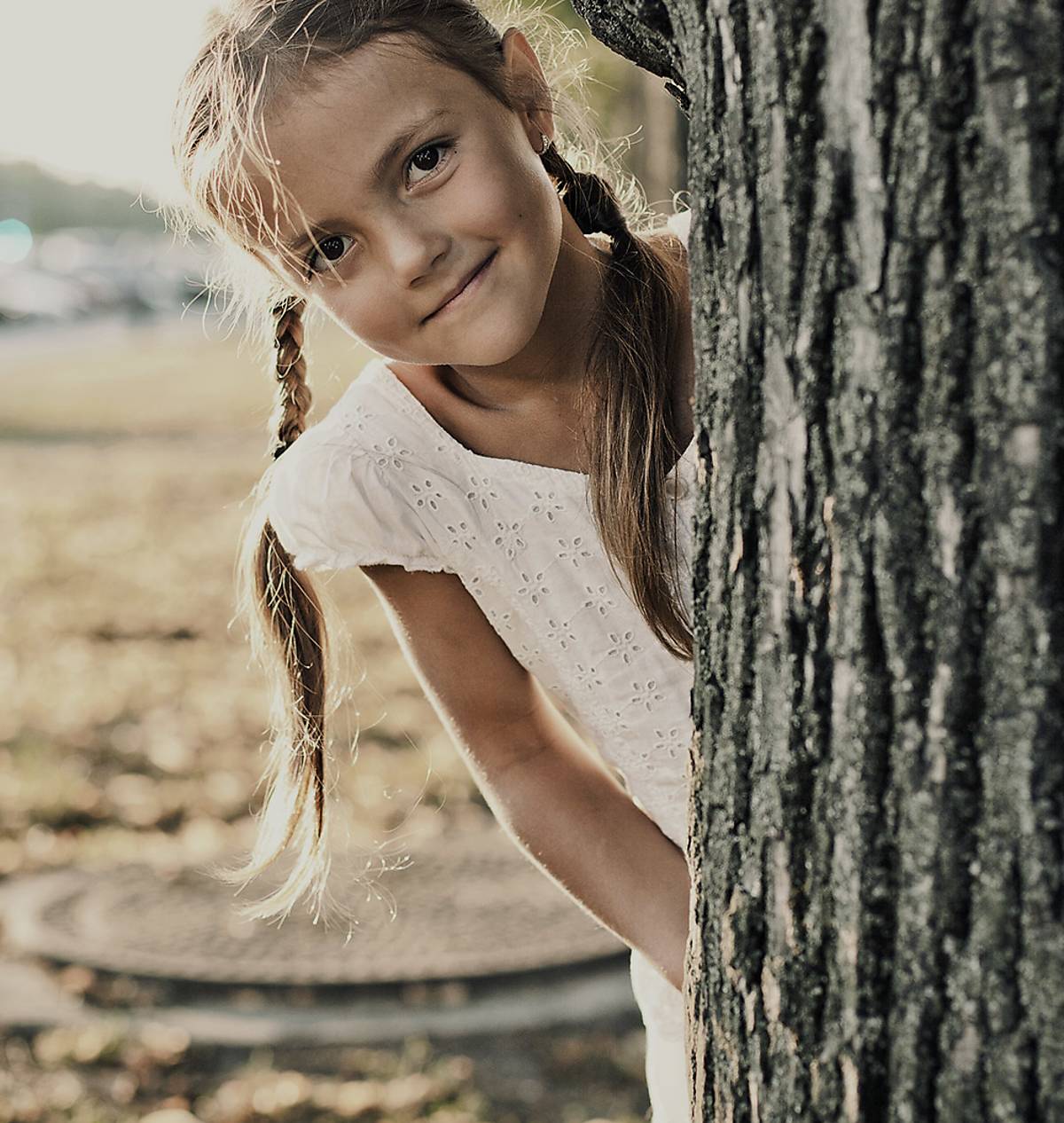 Kind schaut hinter Baum hervor