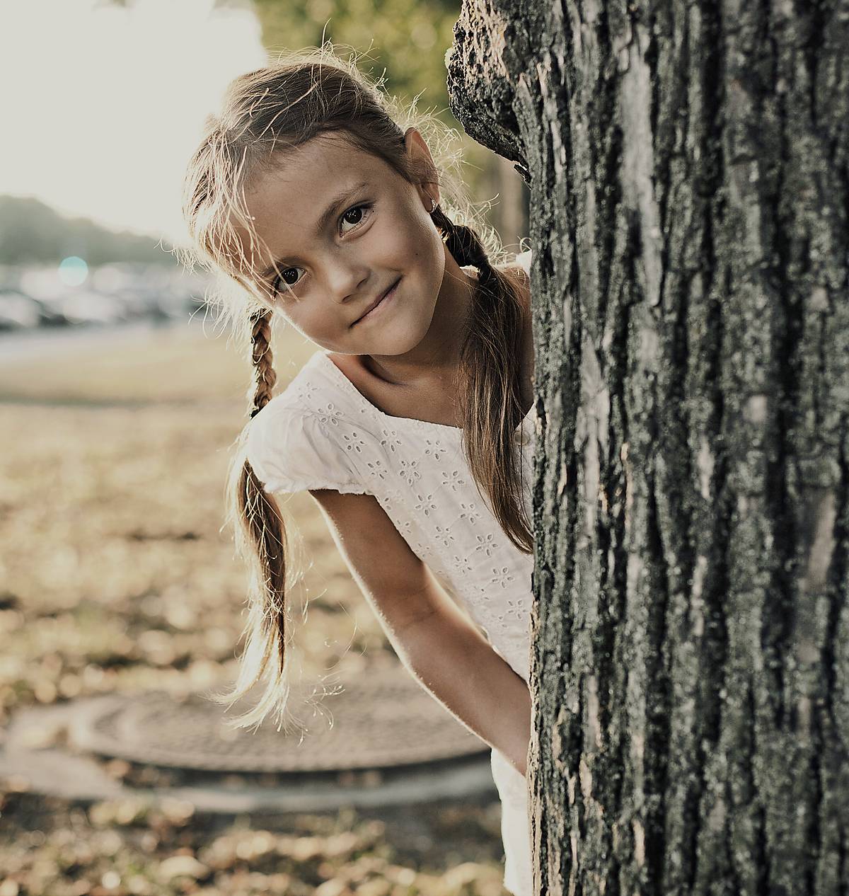 Kind schaut hinter Baum hervor