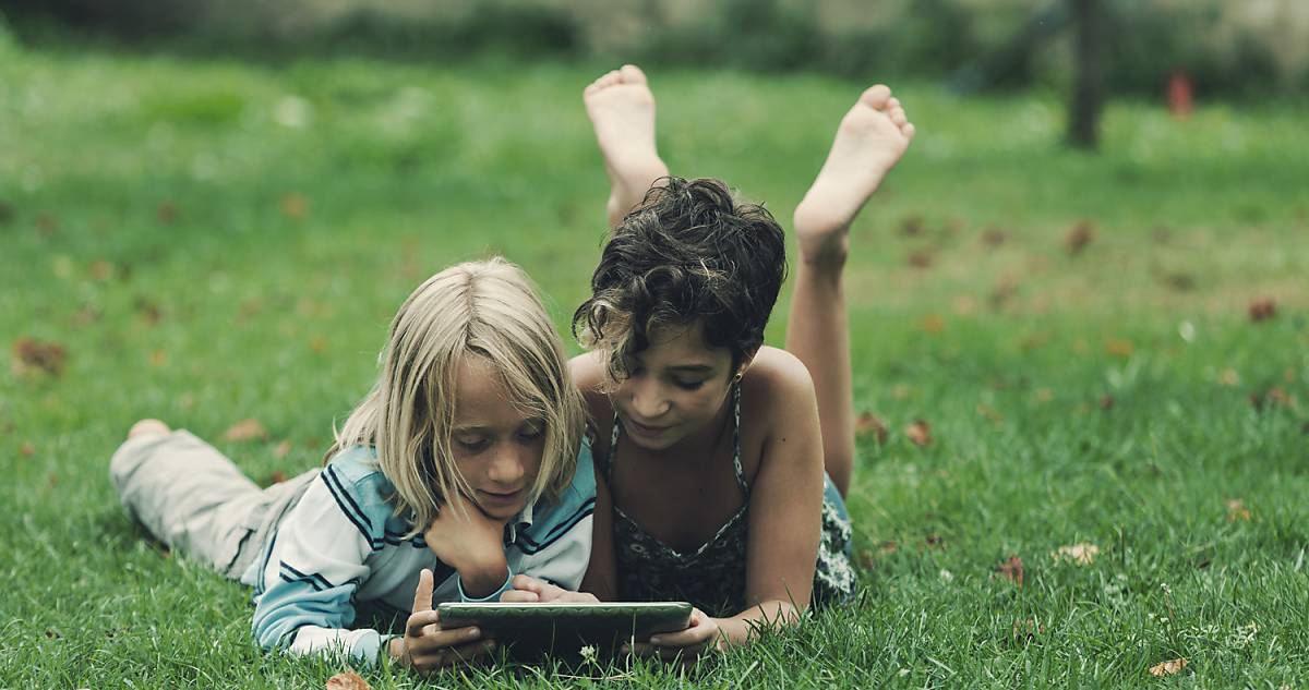 Kinder mit Tablet auf Wiese