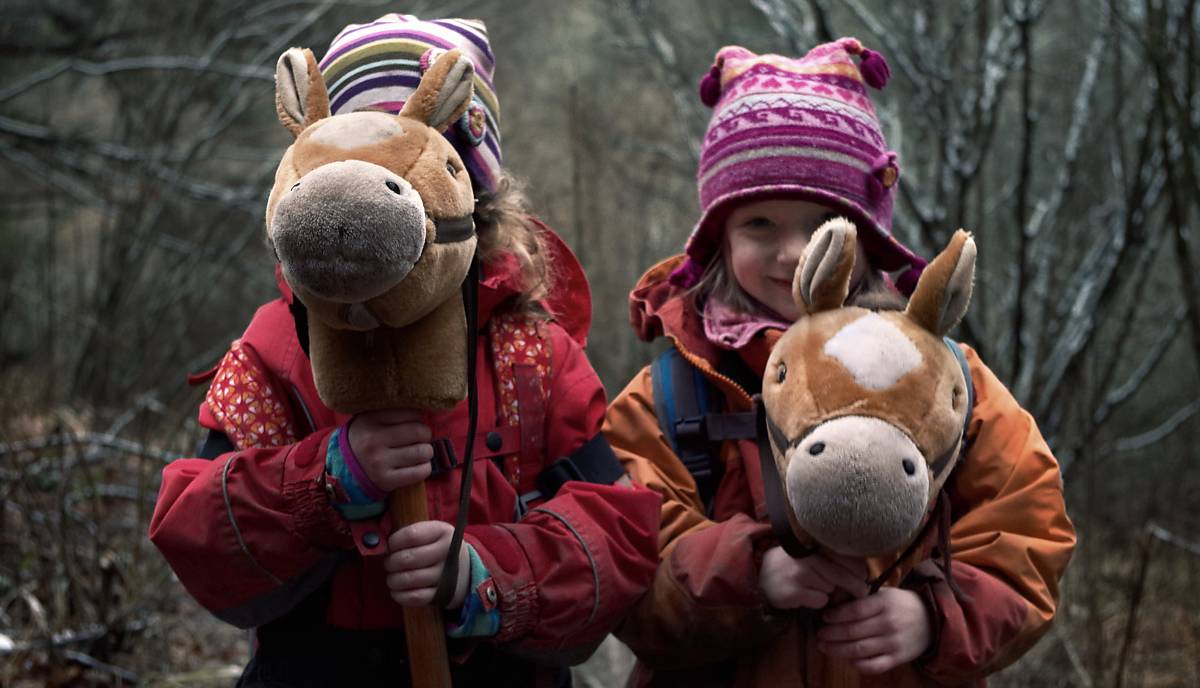 Kinder spielen mit Steckenpferden