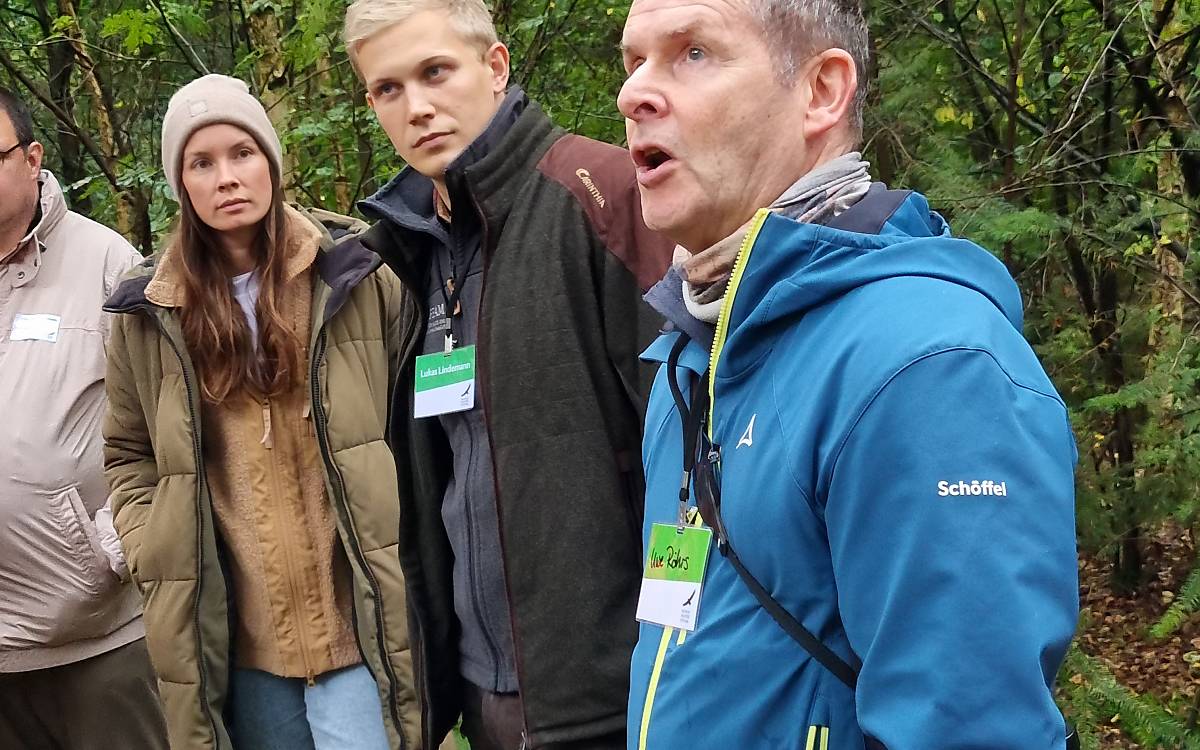 Ornithologe Uwe Röhrs macht die Teilnehmerinnen und Teilnehmer auf markante Vogelstimmen im Wald aufmerksam.