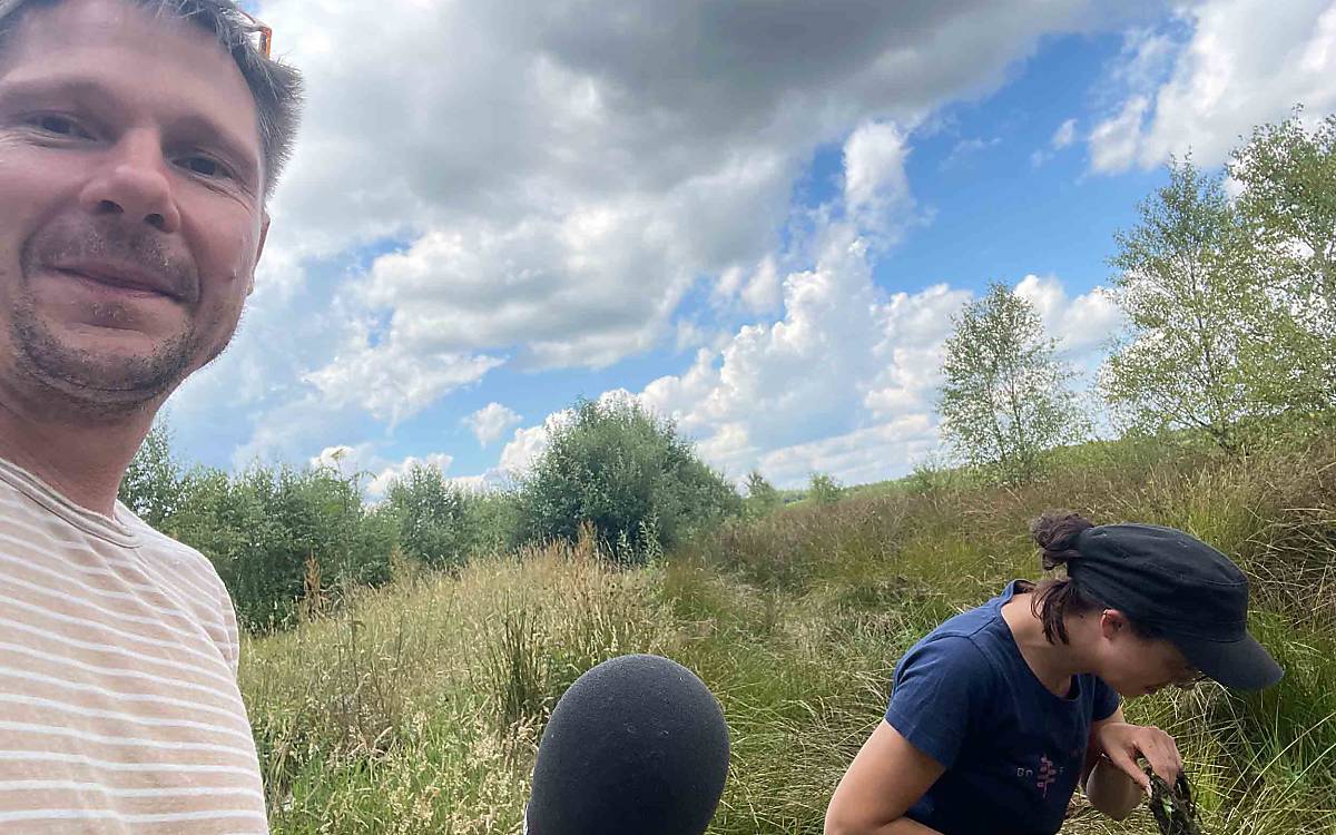 Hendrik schaut beim Keschern zu, als Wildtierexpertin Sophia sich auf die Suche nach Libellenlarven macht.