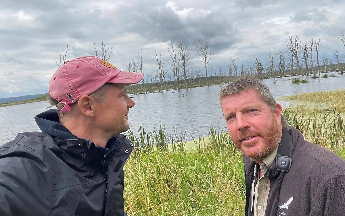 Wildtierreporter Hendrik mit Vogelexperte Michael bei den toten Bäumen, die aus dem Wasser ragen und Vögeln wie dem Seeadler als Schutz und Sichtplatz für die Jagd dienen.