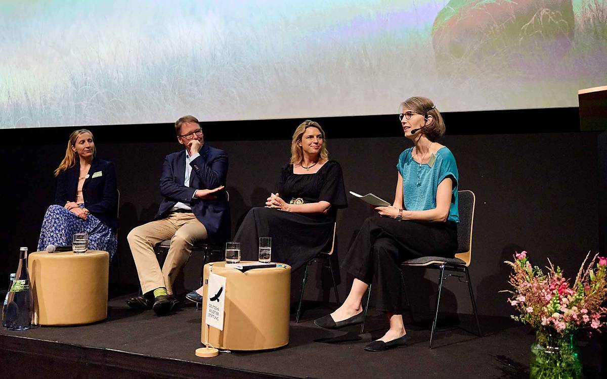 Auf dem Podium diskutierten die Leiterin der KlimaWildnisZentrale Jana Planek von der Naturschutzstiftung David, NABU-Präsident Jörg-Andreas Krüger und Staatssekretärin Sarah Schweizer mit Moderatorin Christiane Röttger (v. l. n. r.), wie neue Trittstein-Vorkommen des Rothirschs ermöglicht werden können.