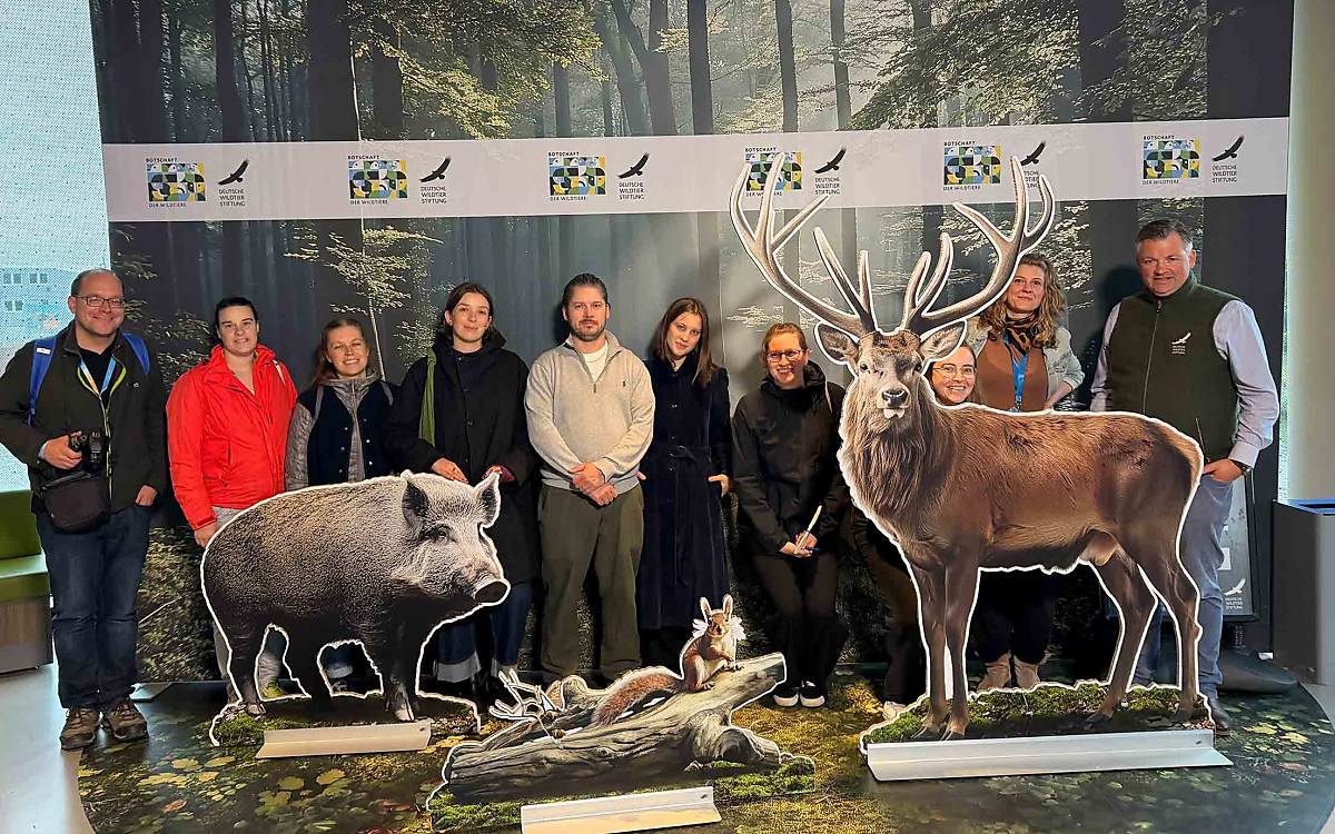 Der Spaziergang führte die Gruppe auch in die Botschaft der Wildtiere – unter anderem zum Fototermin mit den Gastgebern. Ganz rechts Dr. Andreas Kinser, unser Leiter Natur- und Artenschutz, versteckt hinterm Rothirsch Artenschützerin Freya Simonsohn.