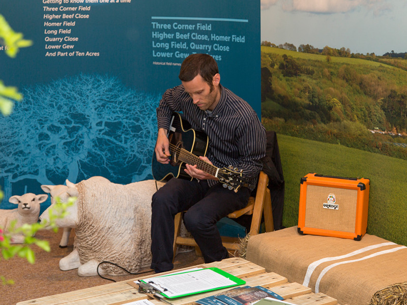 Higher Newham exhibition man playing the guitar next to a plastic sheep