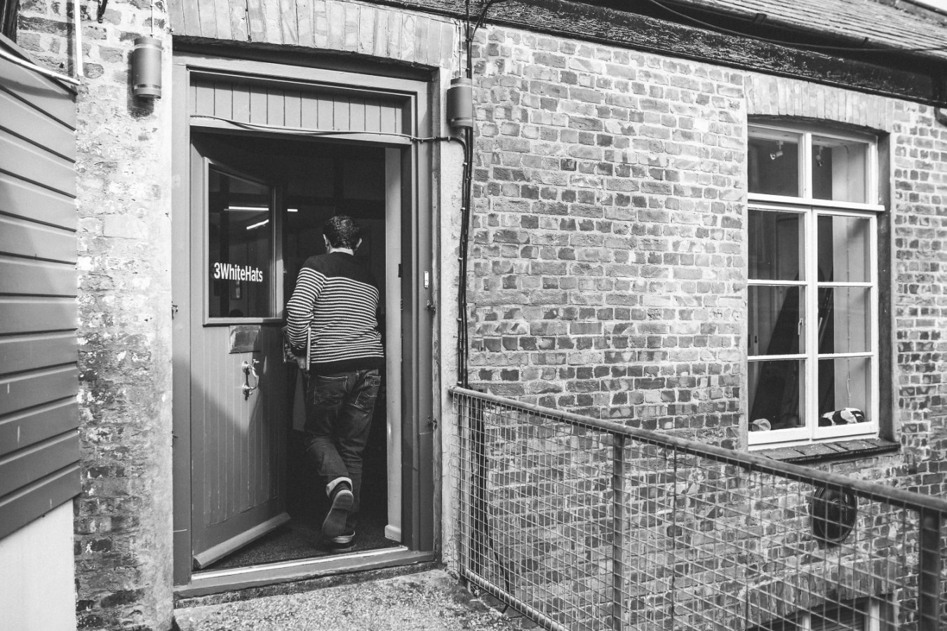 3 white hats building entrance with man walking through the door