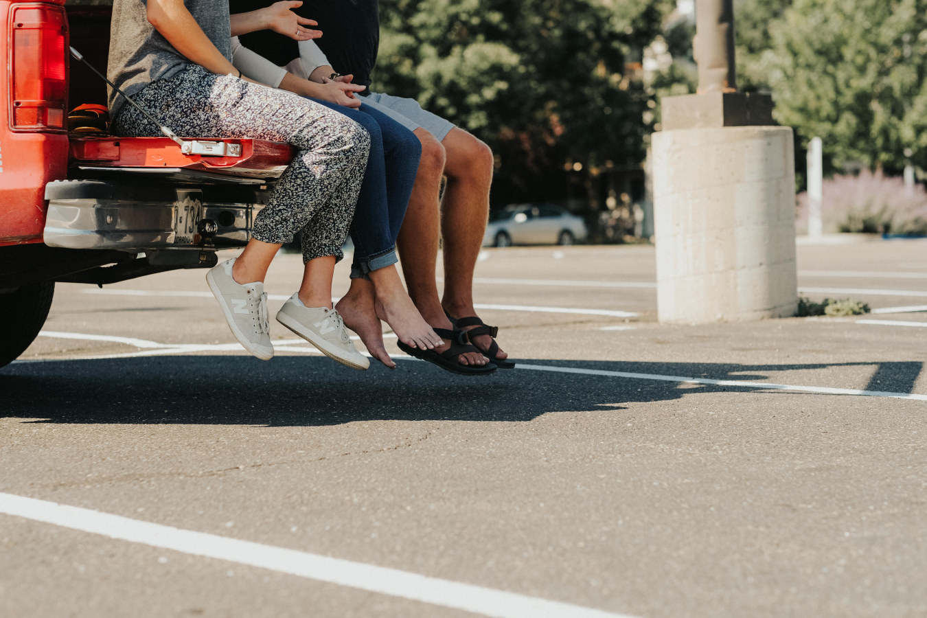 Two people sitting in back of pick up truck, only legs are visible