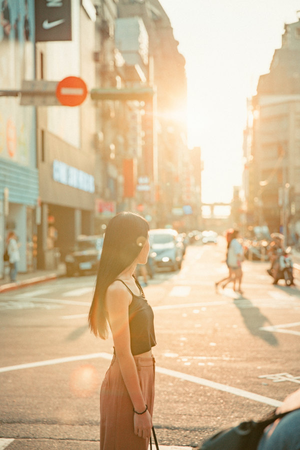 Woman walking across street at sunset in the city