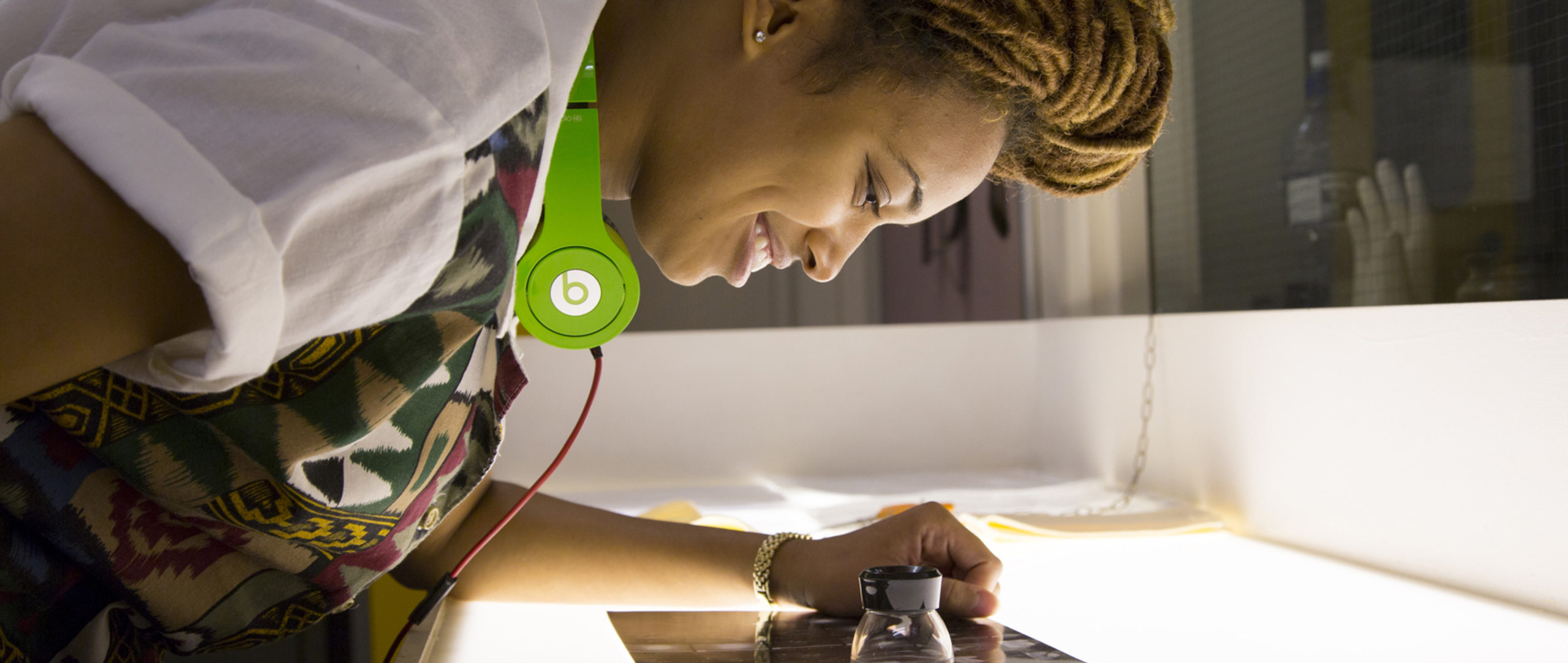 Richmond University image of a young woman wearing beats headphones studying photography