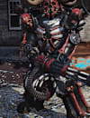 A character in Fallout 76 wearing red and black power armor with a horned helmet, standing on gravel near a rusty car and stone pillars.