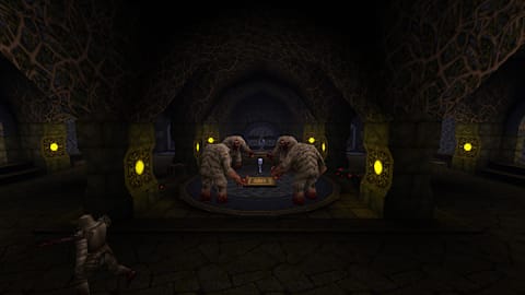 A person wearing armor walking towards a chest in a darkly lit room.