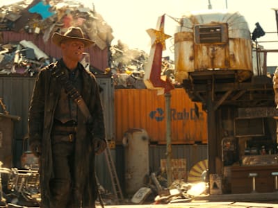 Still from the Fallout TV show. Overseer Hank MacLean stands behind a podium and speaks to the dwellers of Vault 33.