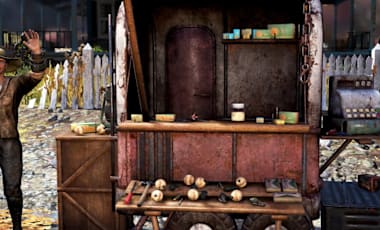 A person stands beside a rusty vendor cart with cans, jars, and a cash register, set in an outdoor area with a white fence, trees, and a swing set.