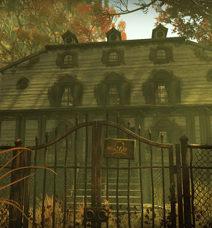 Fallout 76 screenshot of a two-story haunted house with weathered wood, broken windows, and overgrown vegetation. A rusty metal fence with a skull-and-crossbones sign encloses the yard, which has tall dry grass and autumn trees in the background.