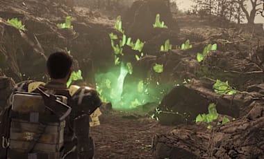 A person walking towards a hole in the ground filled with glowing green crystals.