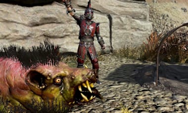 A Fallout 76 character wearing spiked red armor and a gladiator-style helmet stands on rocky ground, raising a clawed weapon in one hand. In the foreground, a mutated creature resembling a boar with pink and green mottled skin, sharp tusks, and a black mane snarls aggressively. To the right is a curved metal shelter frame, and behind them are large stone boulders under a bright sky.