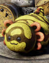 Yellow and black Banded Axolotl plushie rests on a tire amid cracked rocks and yellow radioactive waste barrels in a Fallout 76 wasteland camp