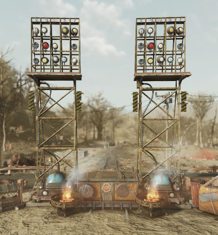 Two tall metal towers with signal lights flank a spiked raider gate, with burning barrels and scrap walls blocking a dusty Appalachian road.