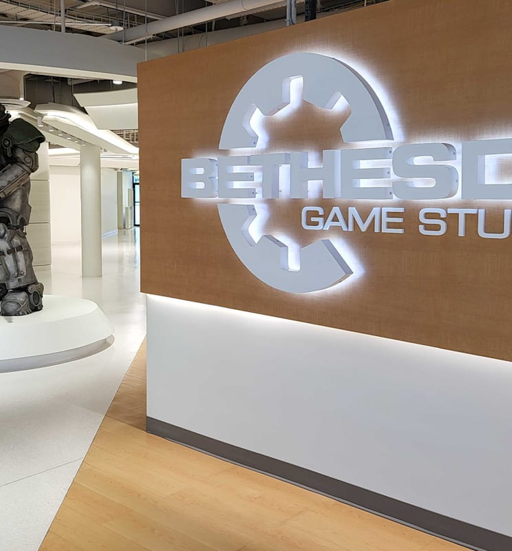 A suit of power armor from the Fallout series stands next to the "Bethesda Game Studios" sign lit in the Bethesda Game Studios lobby.