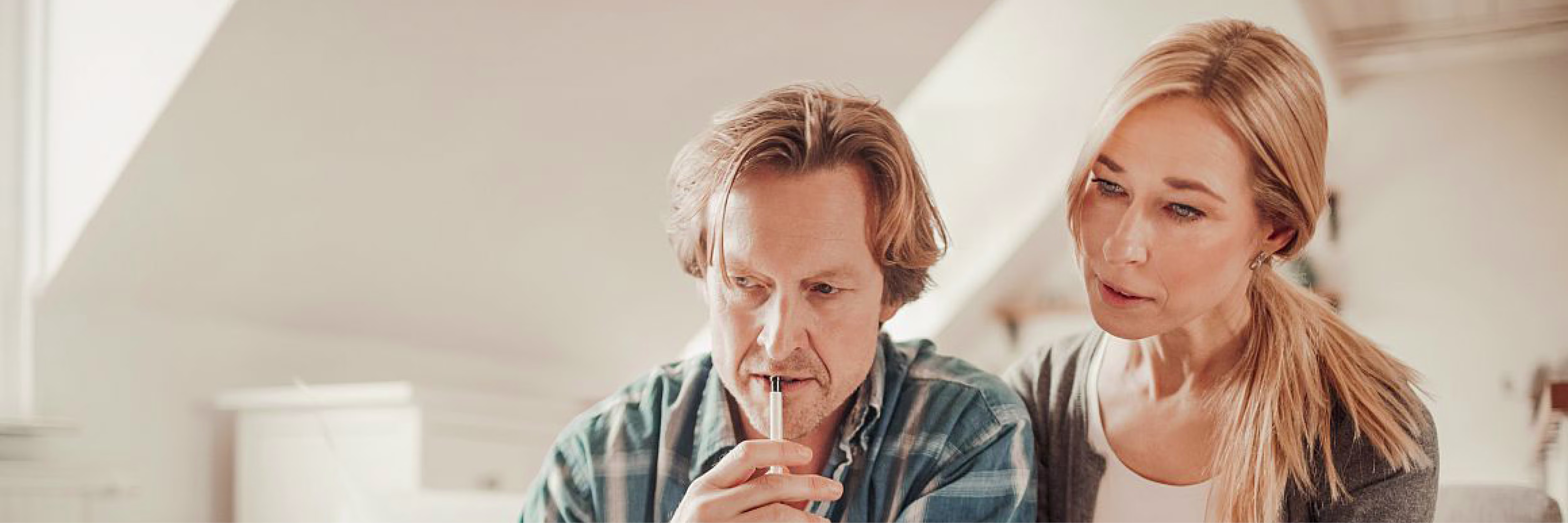 Een man en vrouw bekijken samen documenten op een lichte werkplek, de man houdt een pen vast.