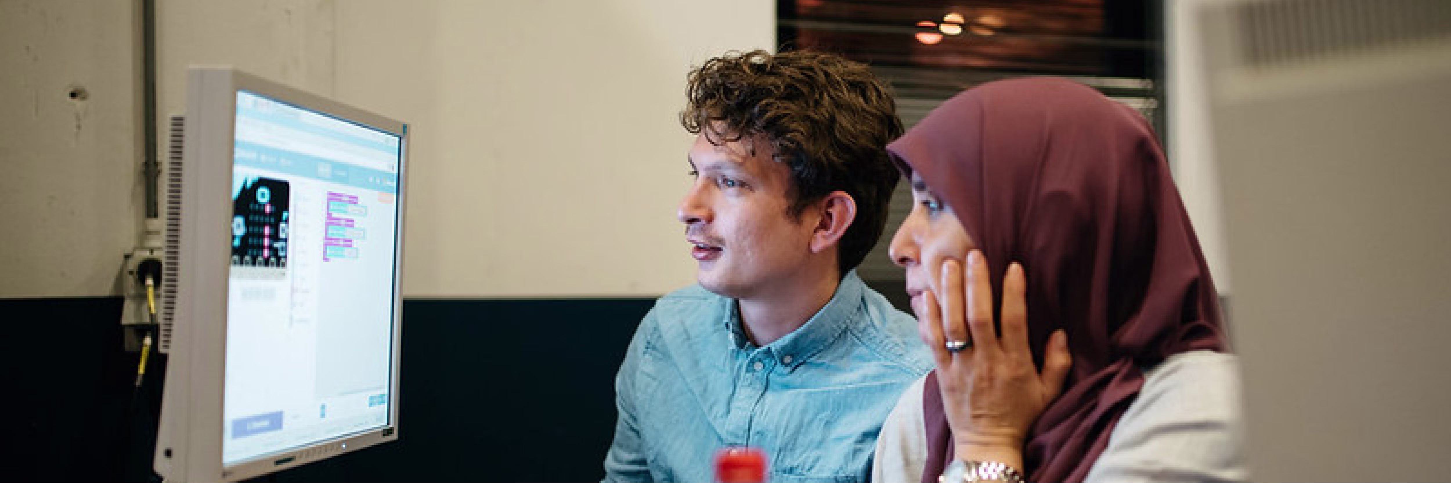 Twee collega's kijken samen naar een computerscherm en bespreken hun werk in een modern kantoor.